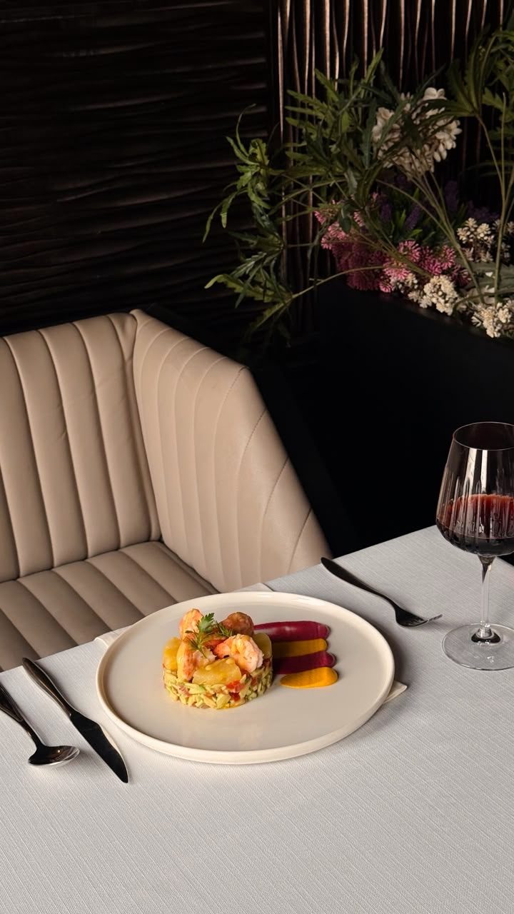 A booth in the Flaminio dining room set with a plated dish and a glass of wine
